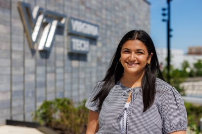 Kaylah Qassis smiling and standing outside the new academic building in Alexandria